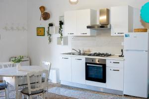 a kitchen with white appliances and a table and a table and chairs at La Dimora delle Coste in Comiso +32 photos