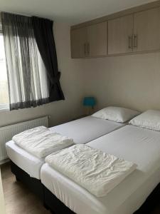 2 camas individuales en un dormitorio con ventana en Meerchalets, en Biggekerke