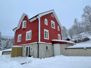 un granero rojo grande con nieve en el suelo en Solbergshyllan en Åre