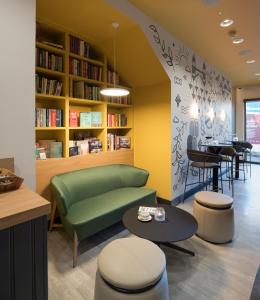 a library with a green couch and a table and chairs at The Wesley Euston in London