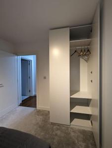 a bedroom with a white closet with shoes in it at NEW Lux 1 or 2 Bed Flats + Car Park + 5min Tube + Fast WiFi in London