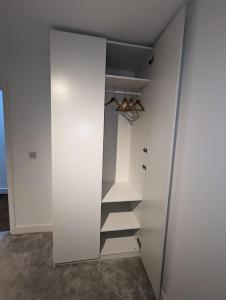 a white closet with a glass door and shelves at NEW Lux 1 or 2 Bed Flats + Car Park + 5min Tube + Fast WiFi in London