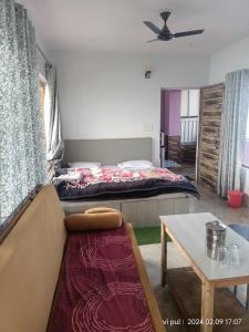 uma sala de estar com uma cama, um sofá e uma mesa em Hotel heavenly heights em Dhanaulti
