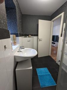baño con lavabo blanco y alfombra azul en Ferienwohnung Selma, en Wilhelmshaven