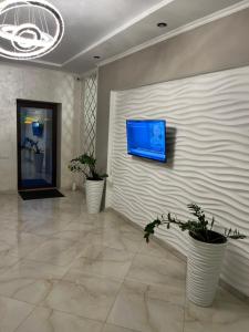 a lobby with two potted plants and a tv on a wall at Holiday house in Vinnytsya