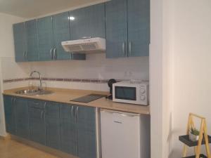 cocina con armarios azules, fregadero y microondas en Casa Damar en Corralejo
