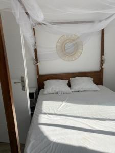 a bedroom with a bed with white sheets and a mirror at LE CABANON DE MARIUS in Six-Fours-les-Plages