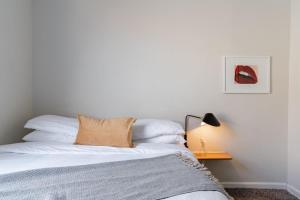 1 dormitorio con 1 cama con sábanas blancas y lámpara en Flexhome Bucktown 2BR C1 - READ INFO, en Chicago