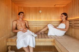 a man and a woman sitting in a sauna at HOODY ACTIVE & HAPPINESS HOTEL in Arco