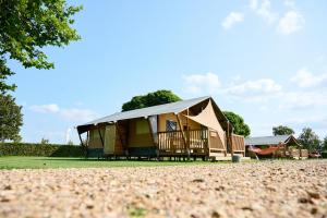 a house with a gambrel roof on a field at Glamping Betuwe in Kesteren