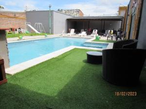 a swimming pool with green grass in a backyard at Alemar Termas Hotel in Termas de Río Hondo