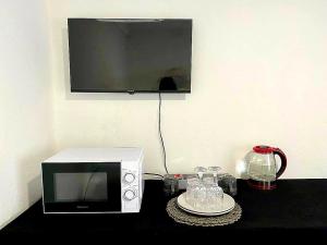 a microwave on a table with a plate and glasses at Peaceful Suburban Utopia in Sandton