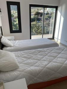 two beds in a bedroom with two large windows at Grand süit 402 in Kalkan