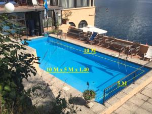 a large blue swimming pool next to the water at Apartments Excelsior in Riva del Garda