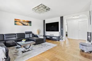 a living room with a black couch and a tv at Fräscht och mysigt enkelrum med eget badrum och dusch in Stockholm