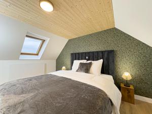 una camera con un grande letto con una parete con accento verde di Mr.Bernard Vakantie Appartementen a De Panne