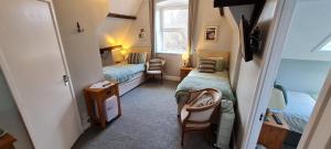 um pequeno quarto com 2 camas e uma janela em The Pendennis Guest House em Penzance