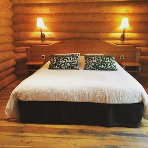 een bed in een houten kamer met 2 lampen bij LOGIS DOMAINE DE FOOLZ 