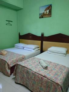 twee bedden in een hotelkamer met een kussen erop bij Adeeva Homestay Langkawi in Pantai Cenang