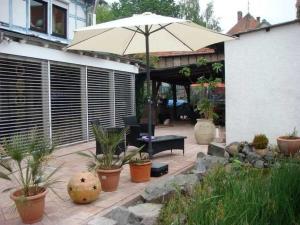 eine Terrasse mit einem Sonnenschirm, einer Bank und Pflanzen in der Unterkunft Klaschter Gastewohnung in Groß-Umstadt