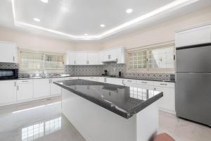 Luxury Emirates Private Villa in Dubai Jumeirah في دبي: مطبخ كبير مع دواليب بيضاء وجزيرة كبيرة