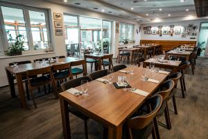 a restaurant with wooden tables and chairs and windows at Šport Hotel *** Donovaly in Donovaly