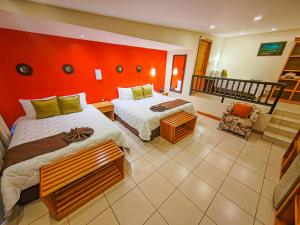 1 dormitorio con 2 camas y pared roja en Hotel & Spa Poco a Poco - Costa Rica en Monteverde Costa Rica
