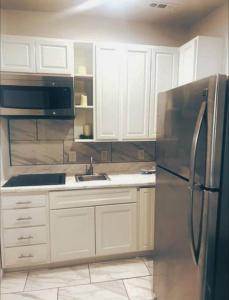 a kitchen with white cabinets and a stainless steel refrigerator at Beautiful Queen Luxury Suite Near Downtown Norfolk in Norfolk
