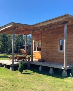 een blokhut met een veranda en een picknicktafel bij La Casona Puelo Lodge in Cochamó