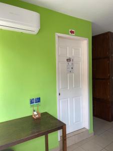 a green room with a white door and a wooden table at Hostal Casa Huasteca in Ciudad Valles