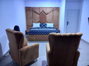 Mega Pavilion Apartment And Suits Gwarinpa في Gwarinpa: غرفة نوم بسرير وكرسيين
