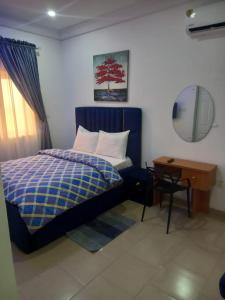 - une chambre avec un lit, une table et un miroir dans l'établissement Mega Pavilion Apartment And Suits Gwarinpa, à Gwarinpa