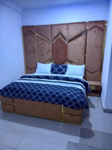 1 dormitorio con 1 cama grande y cabecero grande en Mega Pavilion Apartment And Suits Gwarinpa en Gwarinpa