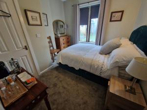 a bedroom with a bed and a window and a table at Briar Cottage Guest Suite in Norwood Green, Halifax in Halifax