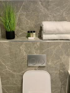 a bathroom with a toilet and towels on a wall at OAM The Paramount Rosebank Luxury One-Bedroom in Johannesburg