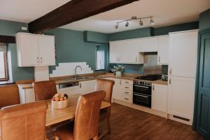 uma cozinha com armários brancos e uma mesa de madeira em Pattys Farm Barn em Cockerham