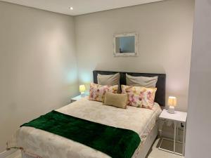 1 dormitorio con 1 cama grande, 2 mesas y espejo en OAM The Paramount Rosebank Luxury One-Bedroom, en Johannesburgo