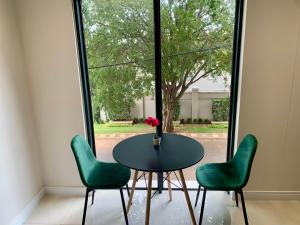 a table with two green chairs and a vase with a flower at OAM The Paramount Houghton Luxury One-Bedroom in Johannesburg