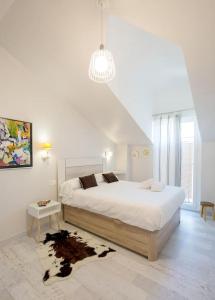 Habitación blanca con cama grande y lámpara de araña. en Katutxo. Basquenjoy en Hondarribia