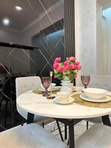 uma mesa de jantar com rosas cor-de-rosa em Luxury two-room apartment with beautiful mountain views em Almaty