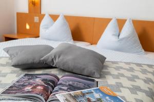 un libro seduto sopra un letto con cuscini di Hotel Rondinella Locarno a Locarno