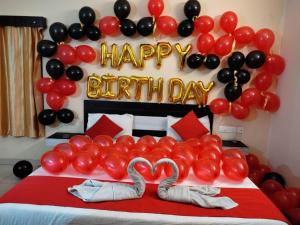 a bed with red and black balloons and a happy birthday sign at Goroomgo Blue Bell Bhubaneswar in Bhubaneshwar