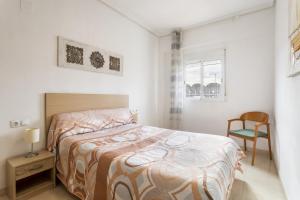 a bedroom with a bed and a chair and a window at Zona Garbí in Valencia