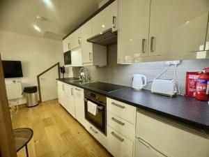 a kitchen with white cabinets and a black counter top at Modern 1 Bedroom self contained apartment in Welwyn Garden City