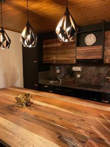 a kitchen with a wooden counter and three lights at Bel appartement près de Verbier in Bovernier