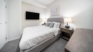 een witte slaapkamer met een bed en een flatscreen-tv bij Landing Modern Apartment with Amazing Amenities (ID4770X14) in Cleveland