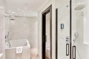 a white bathroom with a shower and a tub at Silken Ciudad Gijón in Gijón