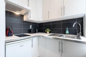 a kitchen with white cabinets and a sink at Lille Gares - Nice equipped apartment in Lille