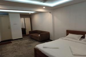 KaglipurにあるAaditya Greensのベッドルーム1室(ベッド1台、椅子付)