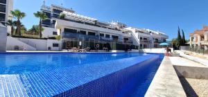 une grande piscine en face d'un bâtiment dans l'établissement Beautiful modern flat with pool in Lomas de Campoamor, à Orihuela